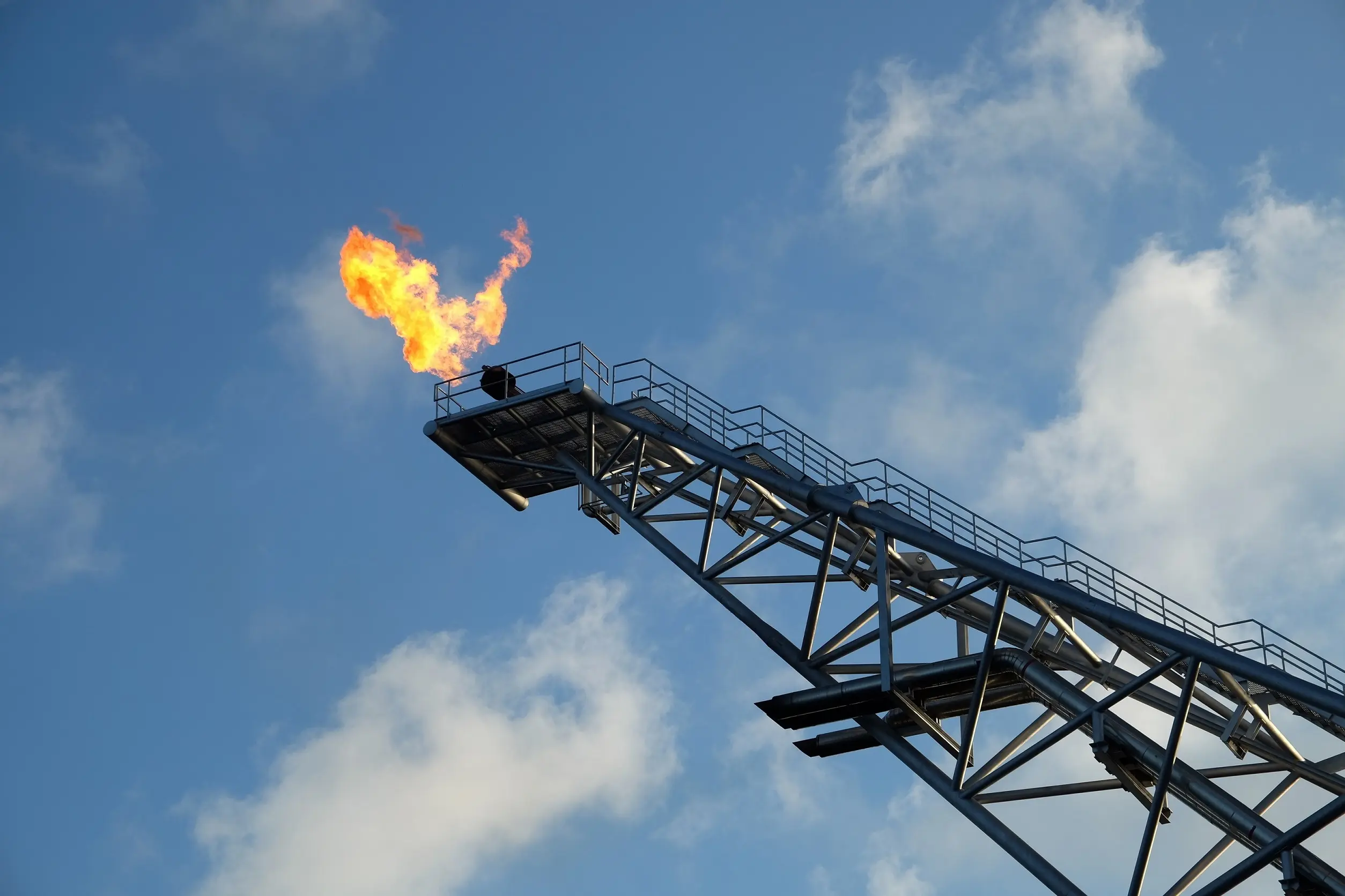 Secteurs : équipementiers et fabricants d'équipements, avec une cheminée de torchère projetant des flammes sur fond de ciel bleu