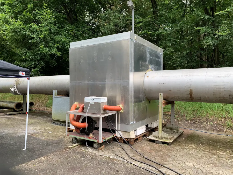 Outdoor testing setup for industrial innovation, featuring large-scale pipes and advanced measurement equipment.