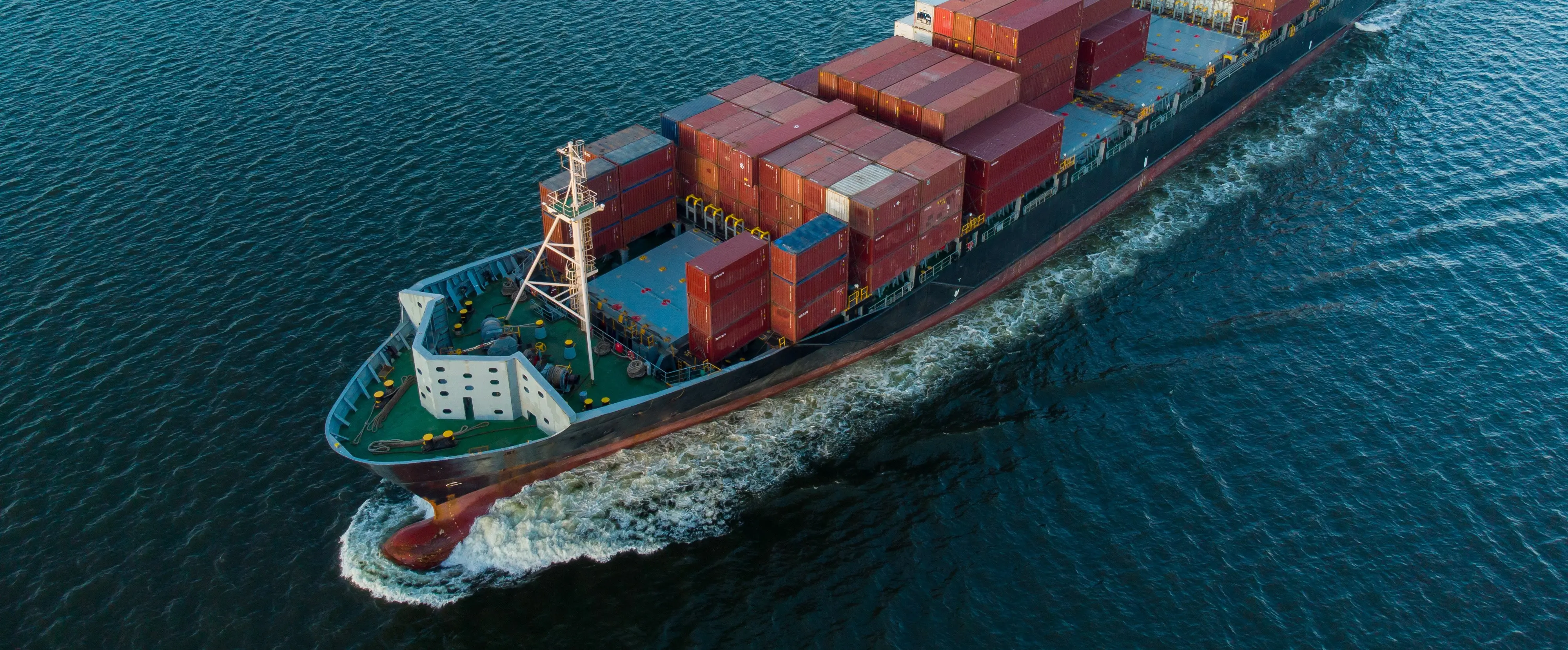Un cargo chargé de conteneurs naviguant sur l'océan, symbolisant les industries maritimes et offshore
