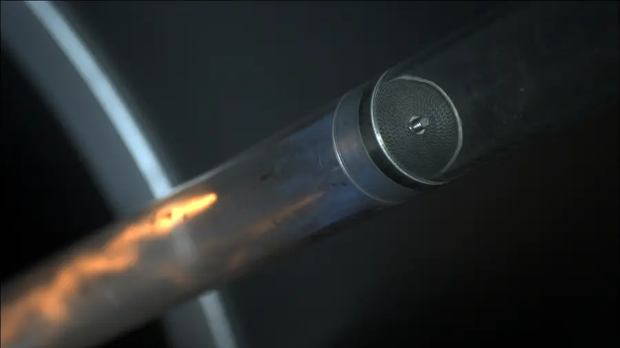 Close-up of a cylindrical metal pipe with an inline flame arrester insert visible inside, illuminated against a dark background during a test.